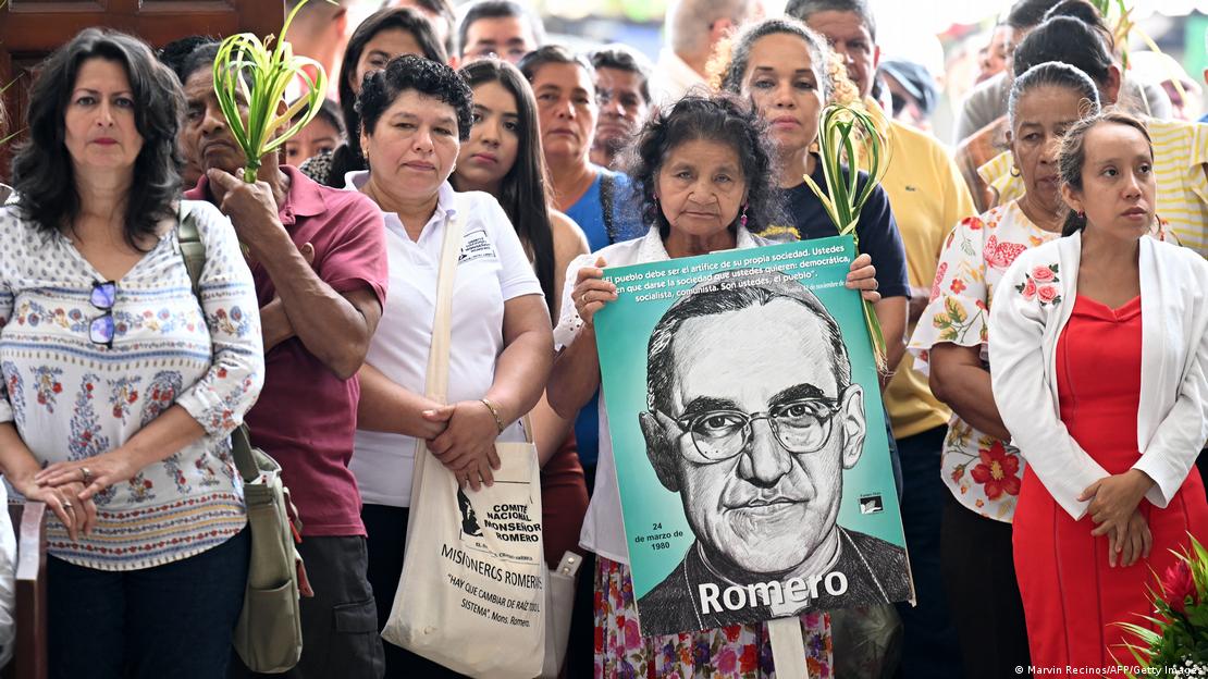 Foto de personas con la imagen de Oscar Arnulfo Romero y palmas del Domingo de Ramos.