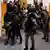 Verdächtige des Terroranschlags auf die Crocus City Hall werden von maskierten Sicherheitskräften in einen Gerichtssaal in Moskau geführt
