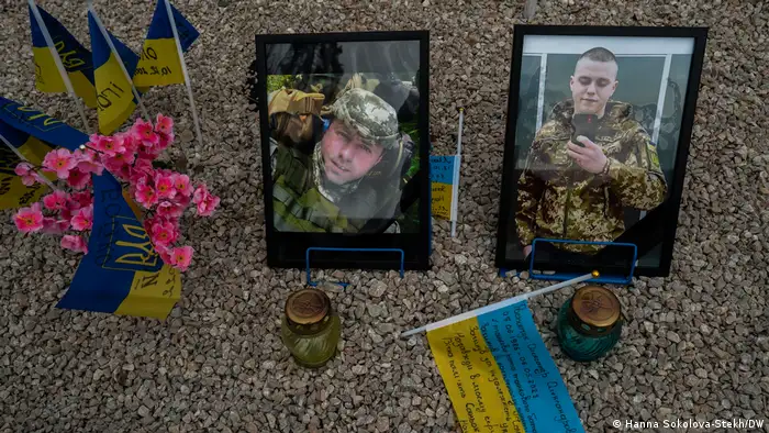Photographs of men killed in Russia's war on Ukraine, surrounded by Urkrainian flags and flowers