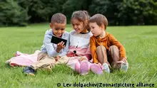 childhood, leisure and technology concept - happy children with smartphone sitting on blanket outdoors || Modellfreigabe vorhanden