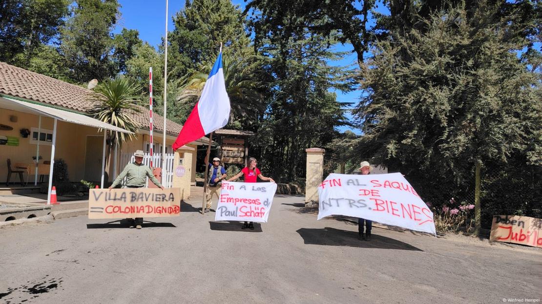 Excolonos de Colonia Dignidad protestan con pancartas y carteles.