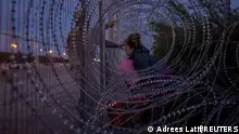 Eliana, 22, a migrant from Venezuela, holds her three-year-old daughter Chrismarlees as she shouts towards an Army National Guard soldier after he halts her from breaching a razor wire-laden fence along the bank of the Rio Grande river in El Paso, Texas, U.S., March 26, 2024. Eliana's six-year-old daughter Ariana was carried past the fence by other migrants, who had used wire cutters to breach the razor wire. REUTERS/Adrees Latif TPX IMAGES OF THE DAY 