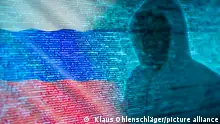 Die Silhouette eines Hackers vor Programmcode und russischer Flagge