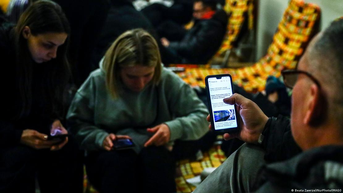 Duas mulheres e um homem usam os smartphones