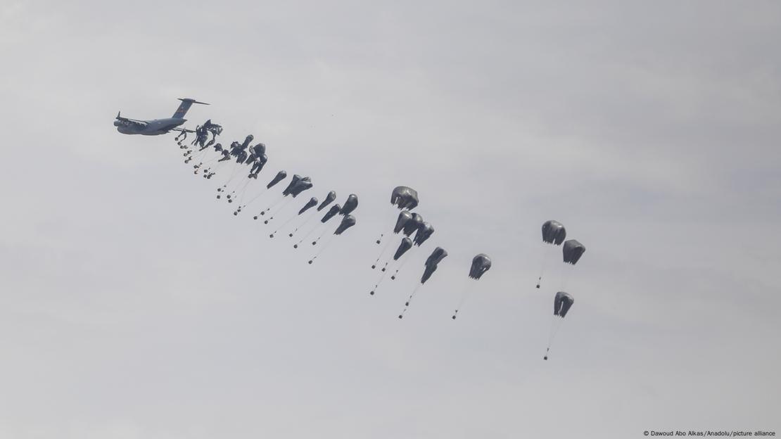 Pacotes de ajuda humanitária com paraquedas caindo de avião