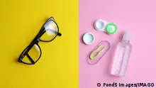 A pair of glasses with a black frame against a yellow background beside contact lense kit on a pink background