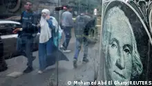 People walk past a currency exchange point, displaying an image of the U.S. dollar, in Cairo, Egypt, March 6, 2024. REUTERS/Mohamed Abd El Ghany