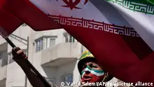 05.04.2024, Iran, Teheran: Ein Mann, dessen Gesicht in den Farben der iranischen Fahne bemalt ist, skandiert Slogans, während er die iranische Fahne bei der jährlichen Kundgebung zum Al-Quds-Tag oder Jerusalem-Tag zur Unterstützung der Palästinenser schwenkt. Bei der Kundgebung nahmen Tausende an einem Trauerzug für die Mitglieder der Revolutionsgarden teil, die bei einem Luftangriff getötet wurden. Mindestens sieben Militärberater des Islamic Revolutionary Guard Corps (IRGC), darunter zwei Generäle, wurden bei einem Luftangriff auf das iranische Konsulat in Syriens Hauptstadt Damaskus am 1. April getötet. Der Iran hat Israel für den Angriff verantwortlich gemacht und droht mit Vergeltung. Foto: Vahid Salemi/AP/dpa +++ dpa-Bildfunk +++