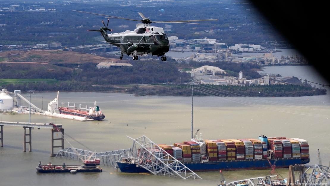 The US presidential helicopter Marine One flies above the wreckage of the collapsed Francis Scott Key Bridge in Baltimore, Maryland; part of the industrial port can be seen in the image, as well as the container ship that caused the collapse