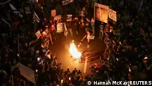 People gather near a fire during a protest against Israeli Prime Minister Benjamin Netanyahu's government and to call for the release of hostages kidnapped in the deadly October 7 attack on Israel by the Palestinian Islamist group Hamas from Gaza, in Tel Aviv, Israel, April 6, 2024. REUTERS/Hannah McKay