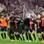 Bayer Leverkusen players and staff link arms to celebrate a win