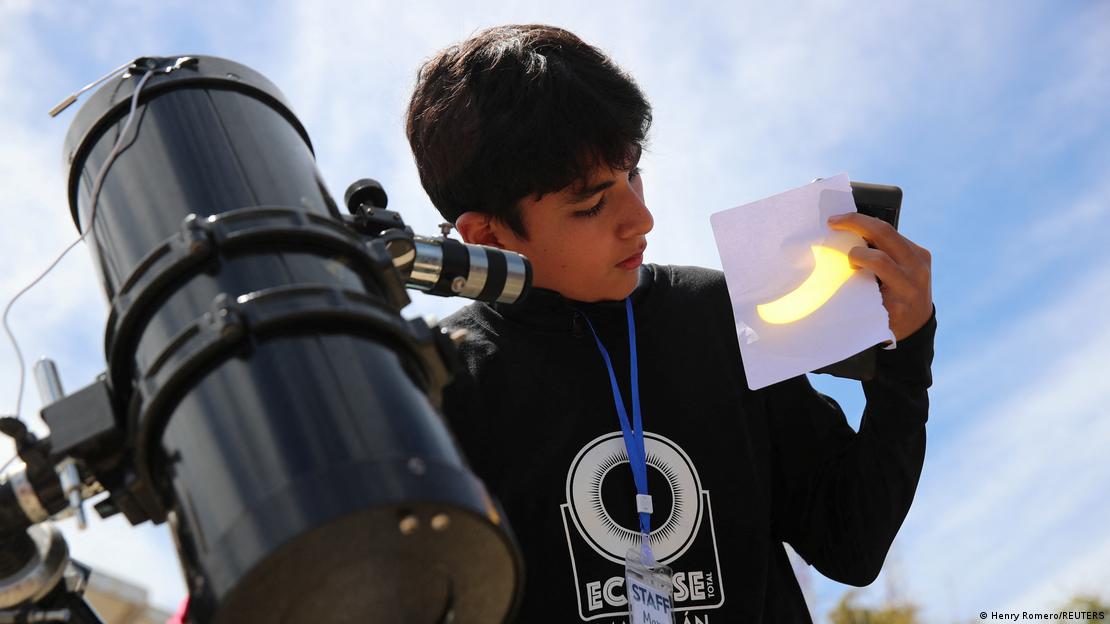 Niño mirando un eclipse solar proyectado en un pedazo de papel.