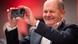 German Chancellor Olaf Scholz holding up an black iPhone German Chancellor Olaf Scholz holding up an black iPhone