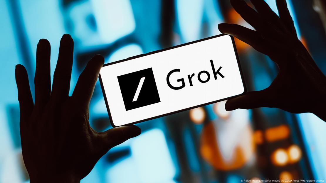 Dos manos sostienen un móvil con el logo de Grok.