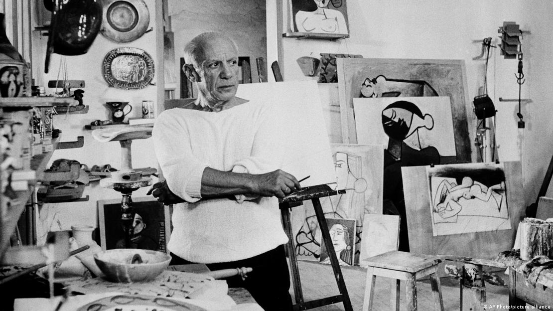 Pablo Picasso em estúdio de trabalho cercado de diversas pinturas