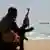 The silhouette of a Somali pirate looking at a ship on the horizon
