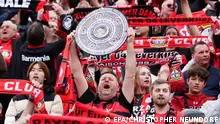 epa11278413 A supporter of Leverkusen lifts a German Bundesliga champion trophy replica during the German Bundesliga soccer match between Bayer 04 Leverkusen and SV Werder Bremen in Leverkusen, Germany, 14 April 2024. EPA/CHRISTOPHER NEUNDORF CONDITIONS - ATTENTION: The DFL regulations prohibit any use of photographs as image sequences and/or quasi-video.