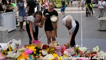 Three women place flowers as a tribute near a crime scene at Bondi Junction in Sydney, Sunday, April 14, 2024, after several people were stabbed to death at a shopping center Saturday. Police have identified Joel Cauchi, 40, as the assailant that stabbed several people to death at a busy Sydney shopping center Saturday before he was fatally shot by a police officer. (AP Photo/Rick Rycroft)