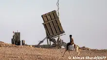 TOPSHOT - A boy rides a donkey near one of the batteries of Israel's Iron Dome missile defence system at a village not recognised by Israeli authorities in the southern Negev desert on April 14, 2024. (Photo by AHMAD GHARABLI / AFP)