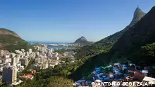 Rio de Janeiro's landmark Christ the Redeemer statue atop Corcovado hill (back, R) spreads its arms over the Botafogo buildings (L), the Rodrigo de Freitas lagoon (C), Ipanema beach (background), as well as the Dona Marta shantytown (R) on August 22, 2012, blending the rich and the poor in the same scenery. A UN report about Latin American and Caribbean cities reveals that 80 percent of the Latin American population concentrates in the cities and that Brazil has the 4th most unequal wealth distribution in the region. AFP PHOTO/ANTONIO SCORZA (Photo by ANTONIO SCORZA / AFP)