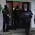 Mehrere vermummte Polizisten gehen durch die Haustür in ein weißes Haus in Solingen