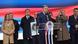 Ein Mann (Milorad Dodik) hinter einem Rednerpult mit Mikrofonen, hinter ihm mehrere Frauen und Männer