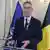 El secretario general de la OTAN durante diez años, Jens Stoltenberg, habla al micrófono con la bandera de la Alianza detrás, así como la belga. 