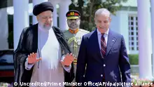 HANDOUT - 22.04.2024, Pakistan, Islamabad: Auf diesem vom Büro des Premierministers veröffentlichten Foto geht der iranische Präsident Ebrahim Raisi (l) mit dem pakistanischen Premierminister Shehbaz Sharif während einer Begrüßungszeremonie im Haus des Premierministers. Foto: Uncredited/Prime Minister Office/AP/dpa - ACHTUNG: Nur zur redaktionellen Verwendung und nur mit vollständiger Nennung des vorstehenden Credits +++ dpa-Bildfunk +++