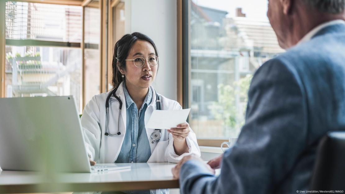 Uma médica conversa com um paciente em um consultório