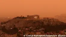 Vista aérea de Atenas, com a Acrópole ao centro, coberta por poeira vermelho-alaranjada