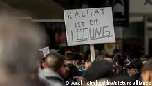 27.04.2024, Hamburg: Teilnehmer einer Islamisten-Demo halten ein Plakat mit der Aufschrift ·Kalifat ist die Lösung· in die Höhe. Foto: Axel Heimken/dpa +++ dpa-Bildfunk +++