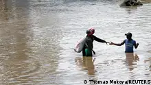 Residents wade through flash flood waters after Athi River burst its banks following heavy rainfall in Kwa Mang'eli settlement of Machakos county near Nairobi, Kenya April 24, 2024. REUTERS/Thomas Mukoya