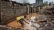 A man carries some belongings in a yellow bag while walking on muddy waters in an area heavily affected by floods in Nairobi, a picture taken on April 25, 2024. A man carries some belongings in a yellow bag while walking on muddy waters in an area heavily affected by floods in Nairobi, a picture taken on April 25, 2024.