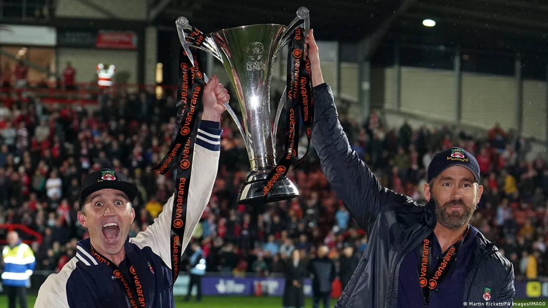 Rob McElhenney y Ryan Reynolds con el trofeo que significa el ascenso de su equipo galés.