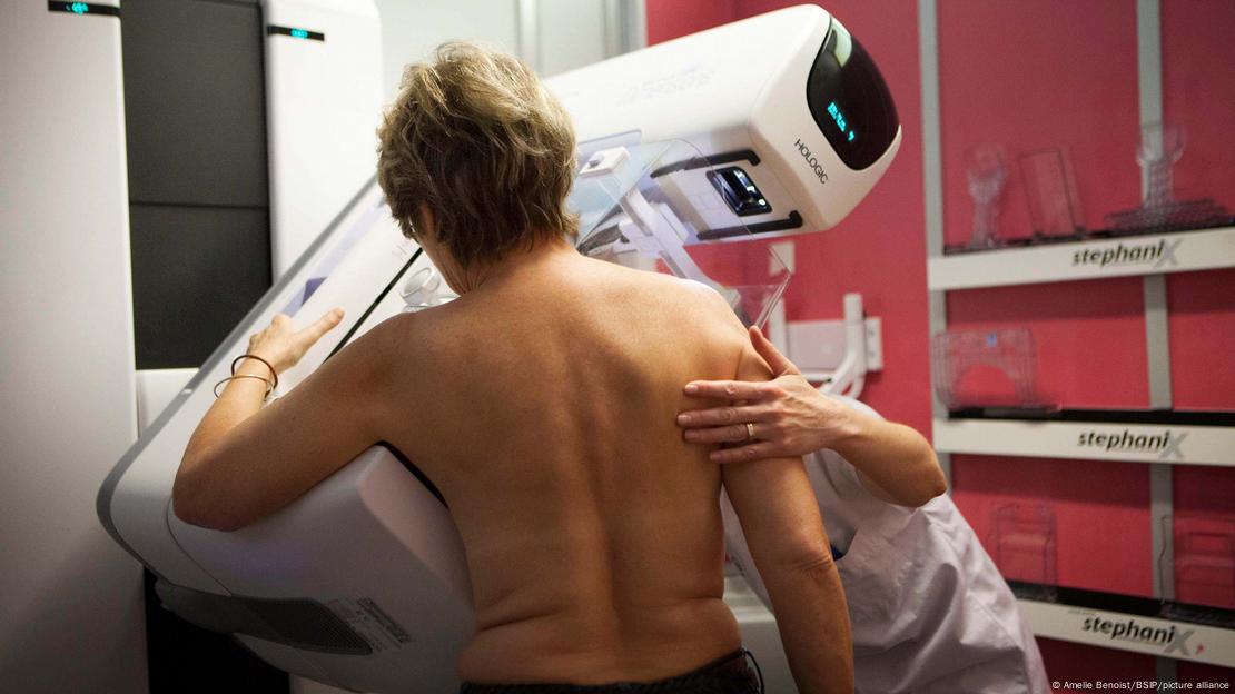 Dijital mamografide sırtı dönük bir kadın ve ona yardımcı olan bir görevli