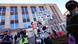 Un manifestante con el rostro cubierto una pancarta, y otras personas, en el campus de la UW-Madison.