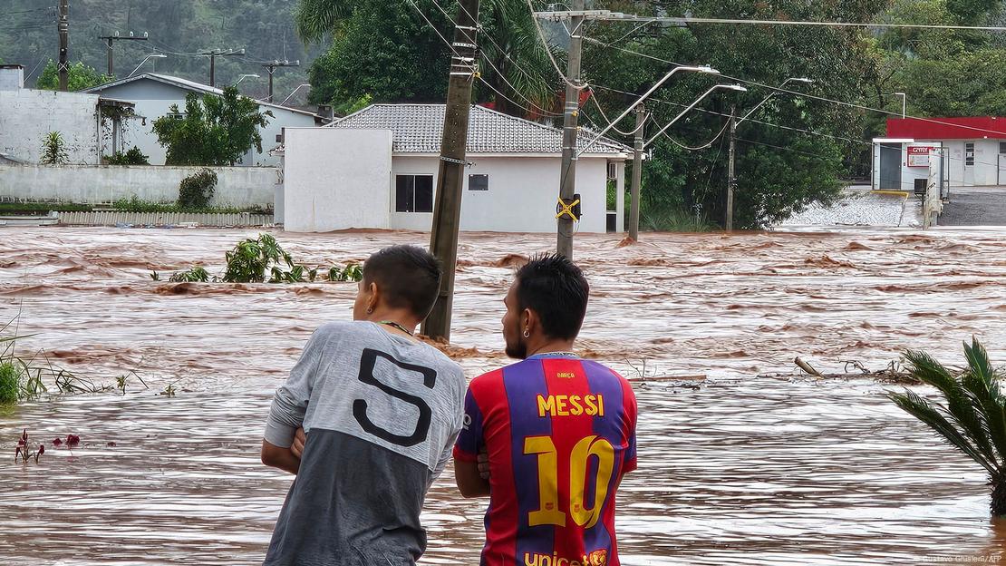 Homens observam ruas alagadas em Encantado