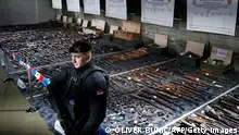 A Serbian police officer stands in front of weapons confiscated in the latest government disarmament action at a police depot near Smederevo, some 40km south of the capital Belgrade, on May 14, 2023, following back-to-back mass shootings in the Balkan country two weeks ago. Serbian President Aleksandar Vucic announced on May 14, 2023 that around 13,500 weapons and mine-explosive devices had been collected, of which around 1,750 were hand grenades, bombs and mortars. Serbia has the highest level of gun ownership in Europe, with roughly 39 out of 100 people owning firearms, according to the Small Arms Survey research group. (Photo by OLIVER BUNIC / AFP) (Photo by OLIVER BUNIC/AFP via Getty Images)