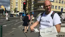 György Zsombor, Chefredakteur von Magyar Hang, verteilt die WOchenzeitung Magyar Hang auf den Straßen von Budapest, Aufnahme von 2018.