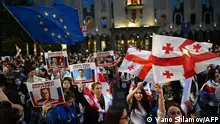 Demonstrators hold a European Union flag, flags of Georgia and placards during a rally outside the Georgian parliament to protest against a controversial foreign influence bill, which Brussels warns would undermine Georgia's European aspirations, in Tbilisi on May 2, 2024. (Photo by Vano SHLAMOV / AFP)