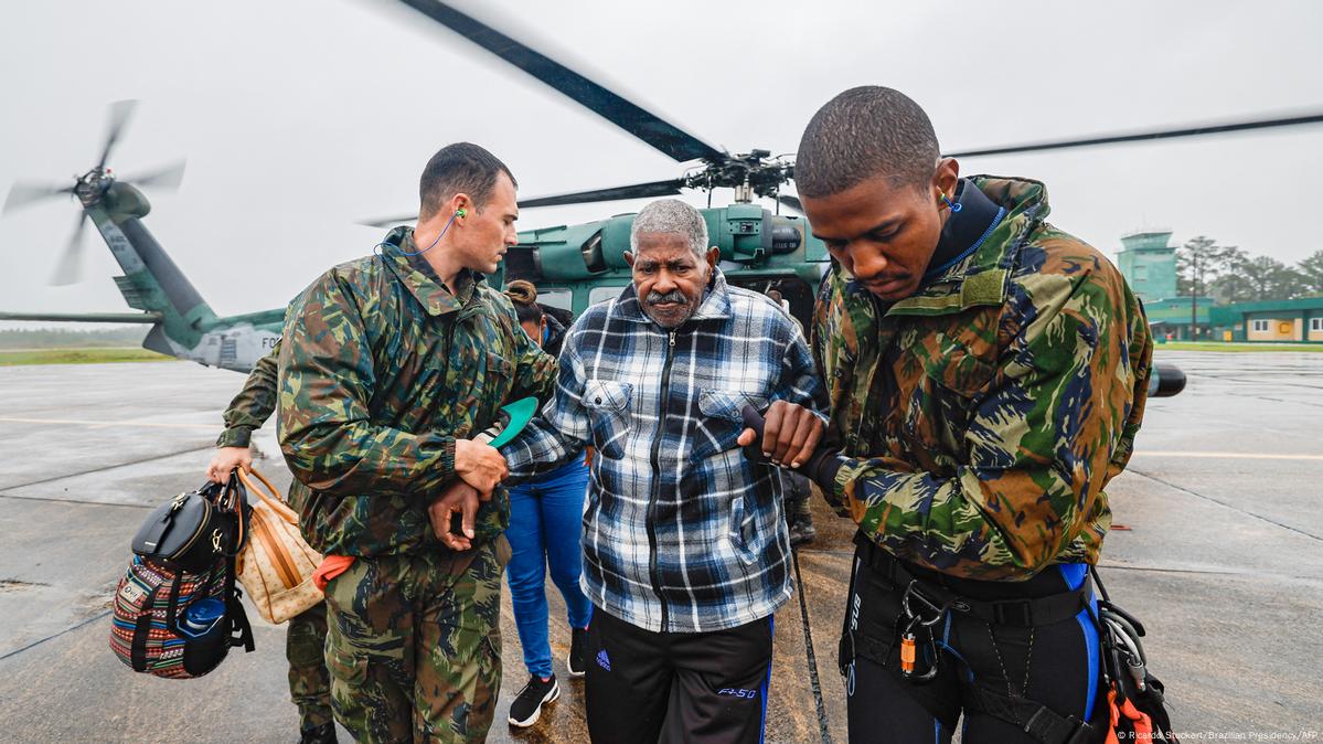 Dos soldados ayudan a un hombre. Detrás de ellos hay un helicóptero.