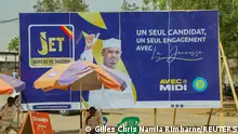 Men sit by a campaign poster of Chadian interim President Mahamat Idriss Deby for the upcoming presidential election, in N'djamena, Chad May 4, 2024. REUTERS/Gilles Chris Namia Rimbarne