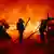 Feuerwehrmänner bekämpfen mit langen Wasserschläuchen einen Großbrand in der ukrainischen Stadt Charkiw, der durch einen russischen Drohnen-Angriff ausgelöst wurde