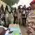 Un soldat, à droite de l'image, qui vote avec un jour d'avance sur le reste de la population, se tient devant des assesseurs de bureau de vote, pour la présidentielle au Tchad. Au second plan des photographes immortalisent la scène
