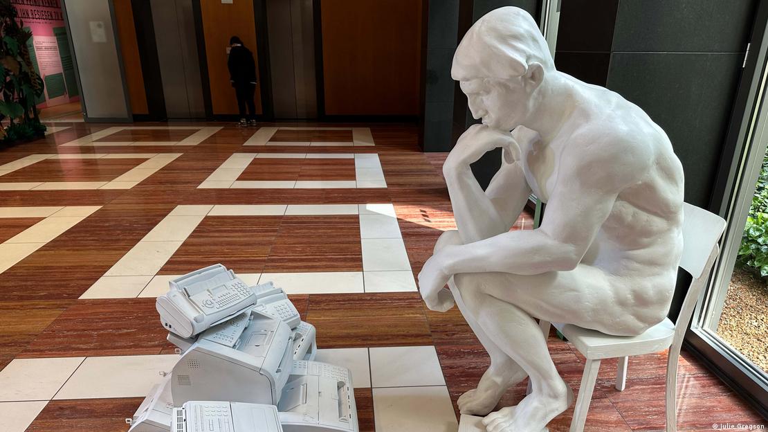 Una escultura de un hombre sentado frente a un fax.