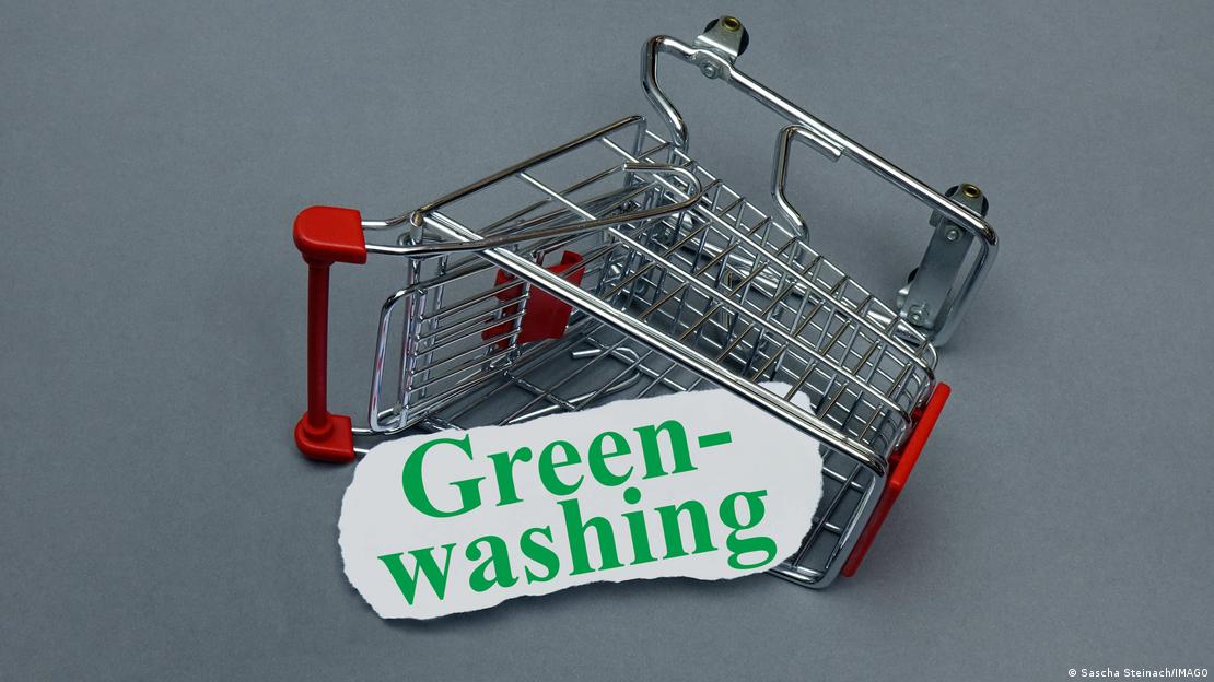 Πεσμένο καρότσι σούπερ-μάρκετ με ένα μεγάλο χαρτόνι που γράφει "Greenwashing"