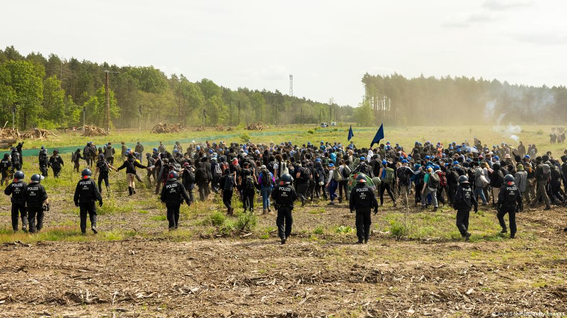 Hundreds of protesters running through a field