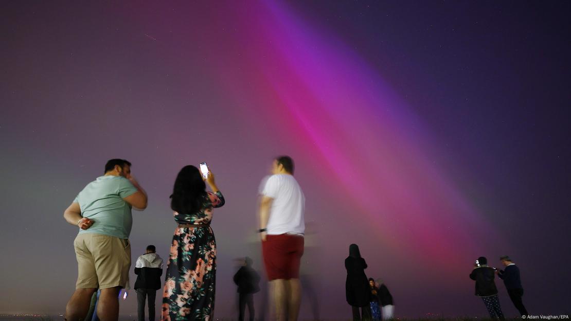 La gente se reunió en la playa de Crosby para contemplar la aurora polar, también conocida como aurora boreal, en Crosby, Gran Bretaña.