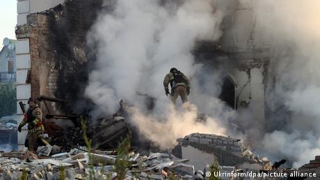 Auf dem Bild sieht man einen Feuerwehrmann, der die Trümmer eines Hauses betritt. Um ihn herum ist Qualm.