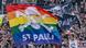 Two large banners, one black the other rainbow colored, read St Pauli and fly over a crowd in a stadium Two large banners, one black the other rainbow colored, read St Pauli and fly over a crowd in a stadium